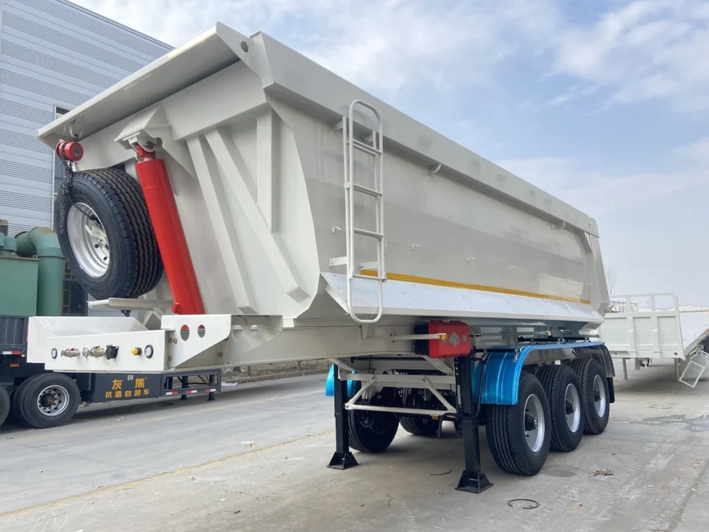 Three-axle rear tipper with a front cylinder and mounted spare wheel