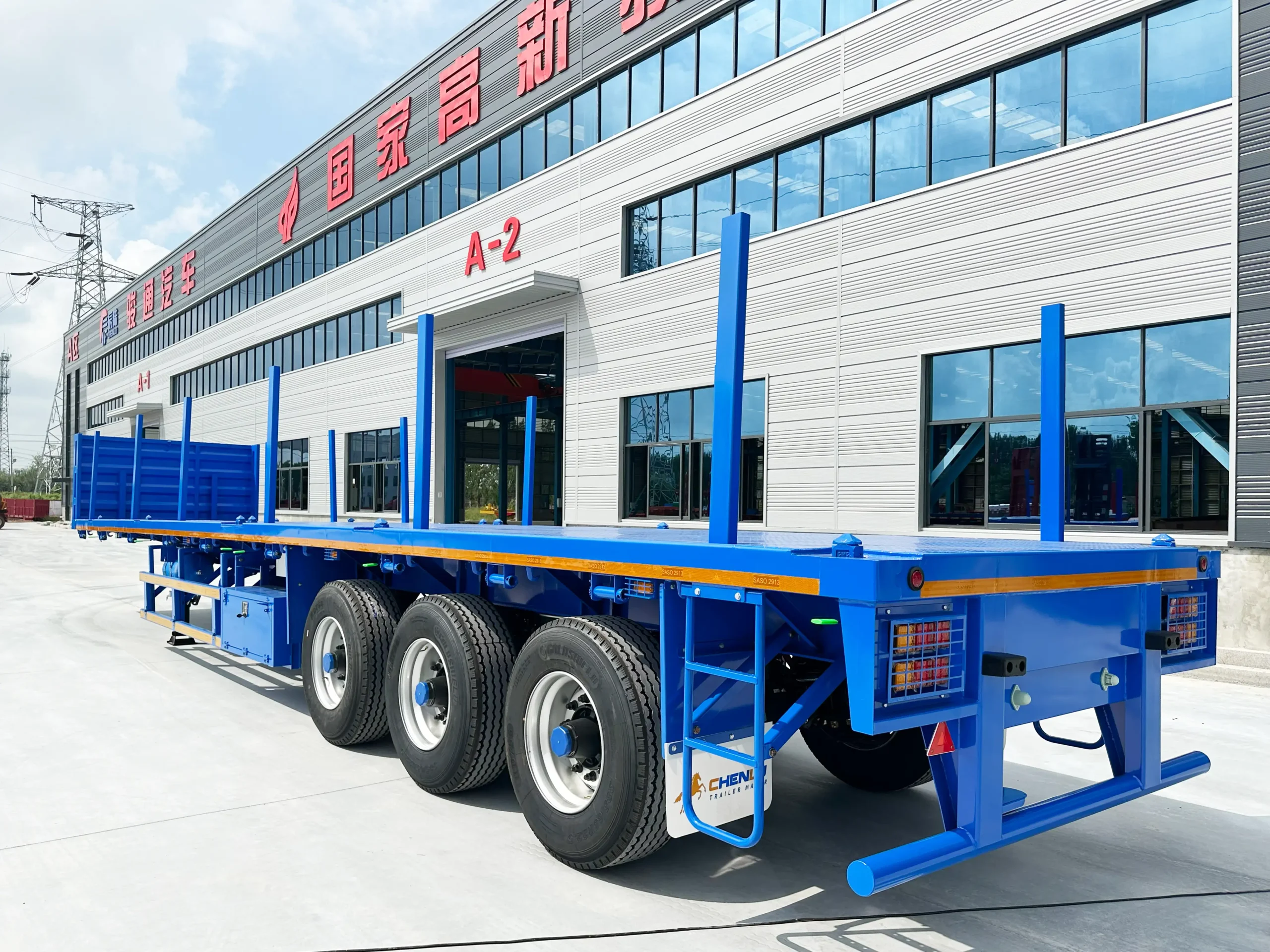 Side view of a three-axle flatbed semi trailer