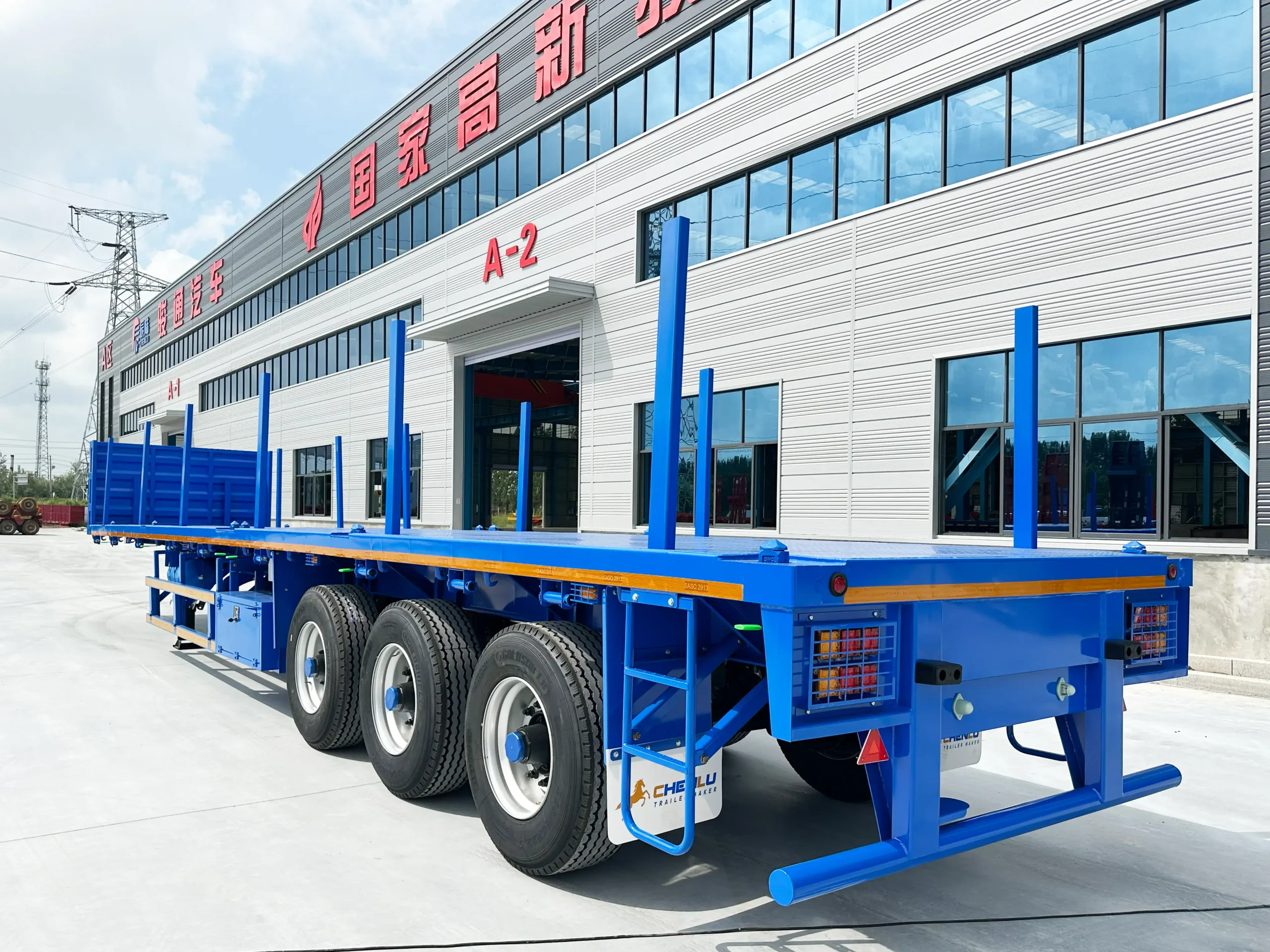 Side view of a three-axle stake flatbed semi-trailer