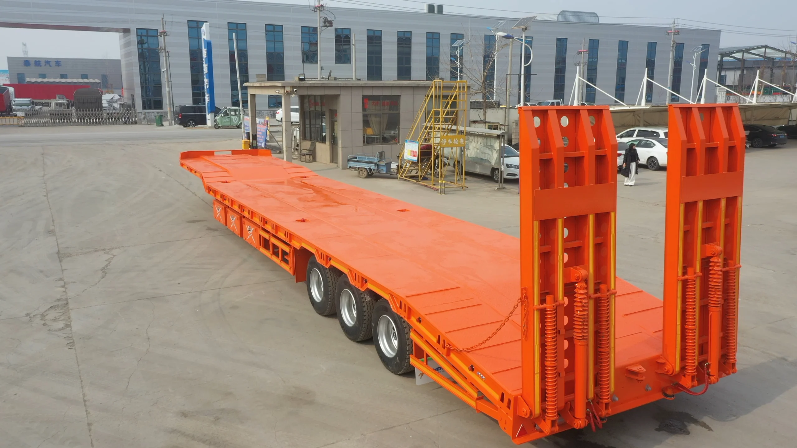 Orange 13m three-axle lowbed semi trailer with rear loading ramps