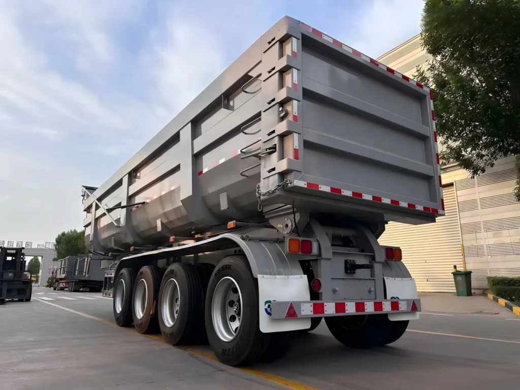 Grey four-axle dump semi-trailer viewed from the rear quarter