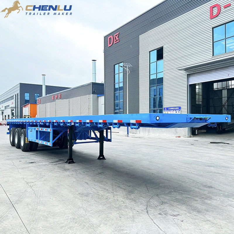 Blue three-axle flatbed trailer viewed from the front corner with landing legs beneath the deck