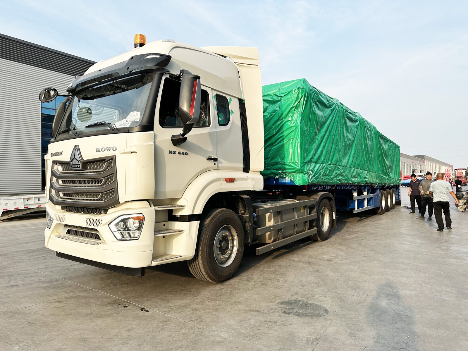 Blue three-axle flatbed semi-trailer with a covered load prepared for Chile