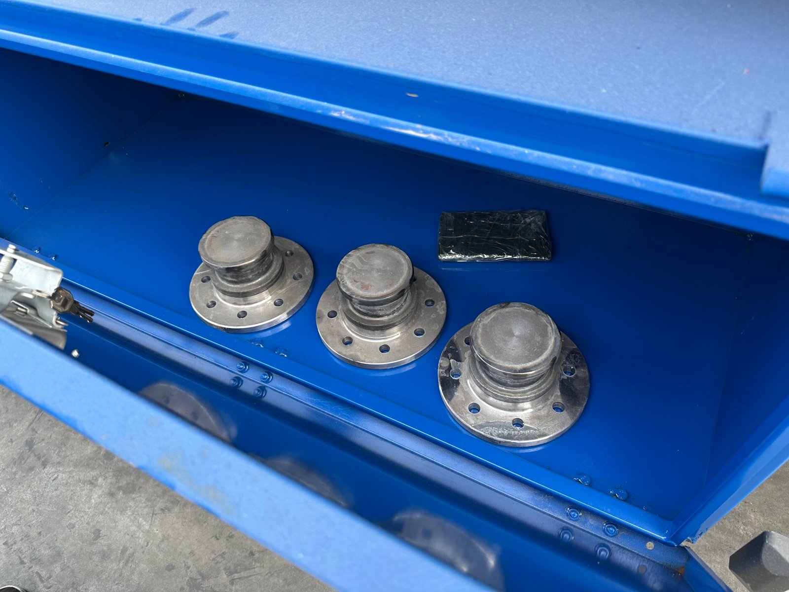 Three spare kingpins stored inside the flatbed trailer toolbox