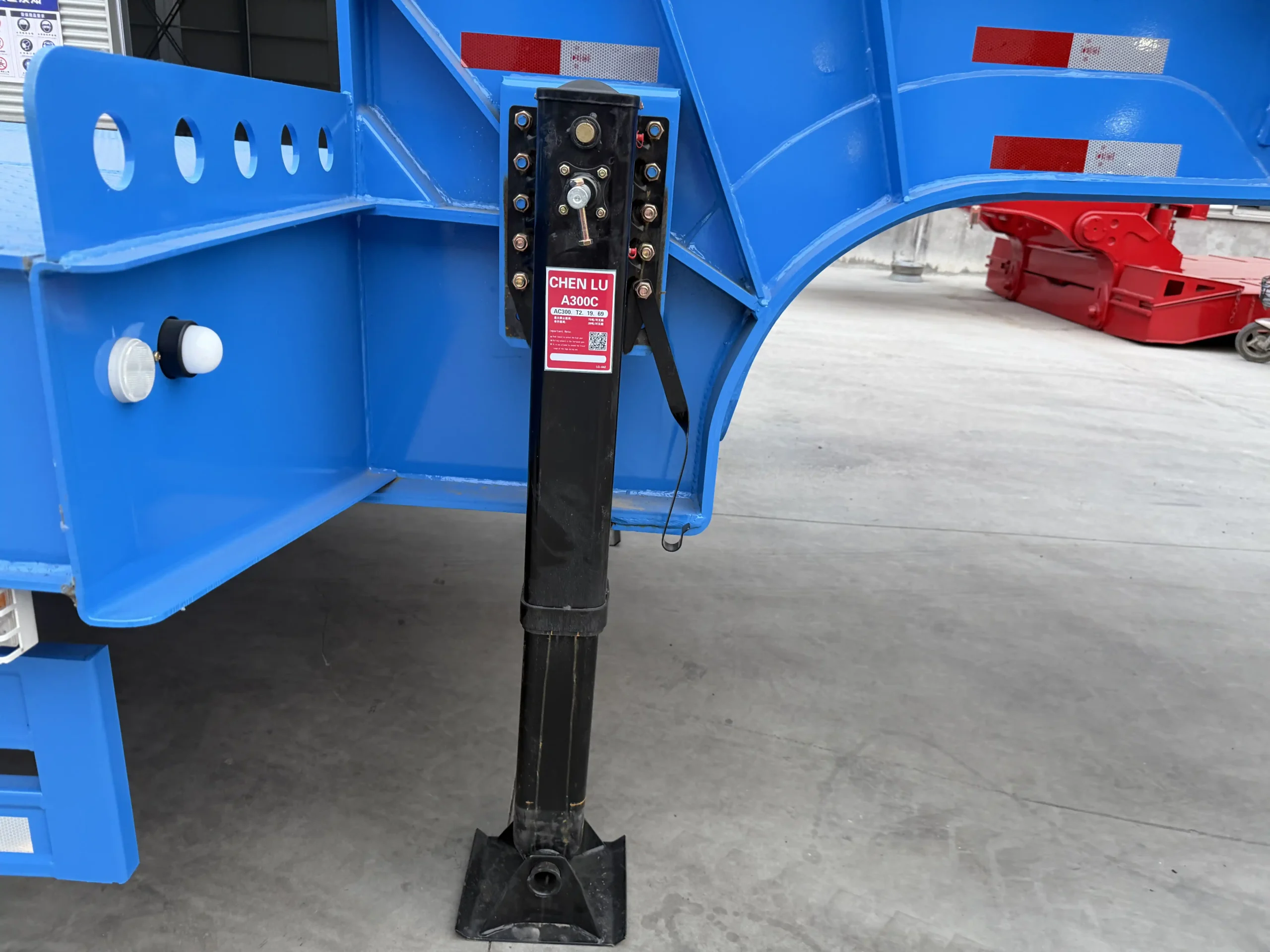 Landing gear below the fixed gooseneck of a blue lowbed trailer