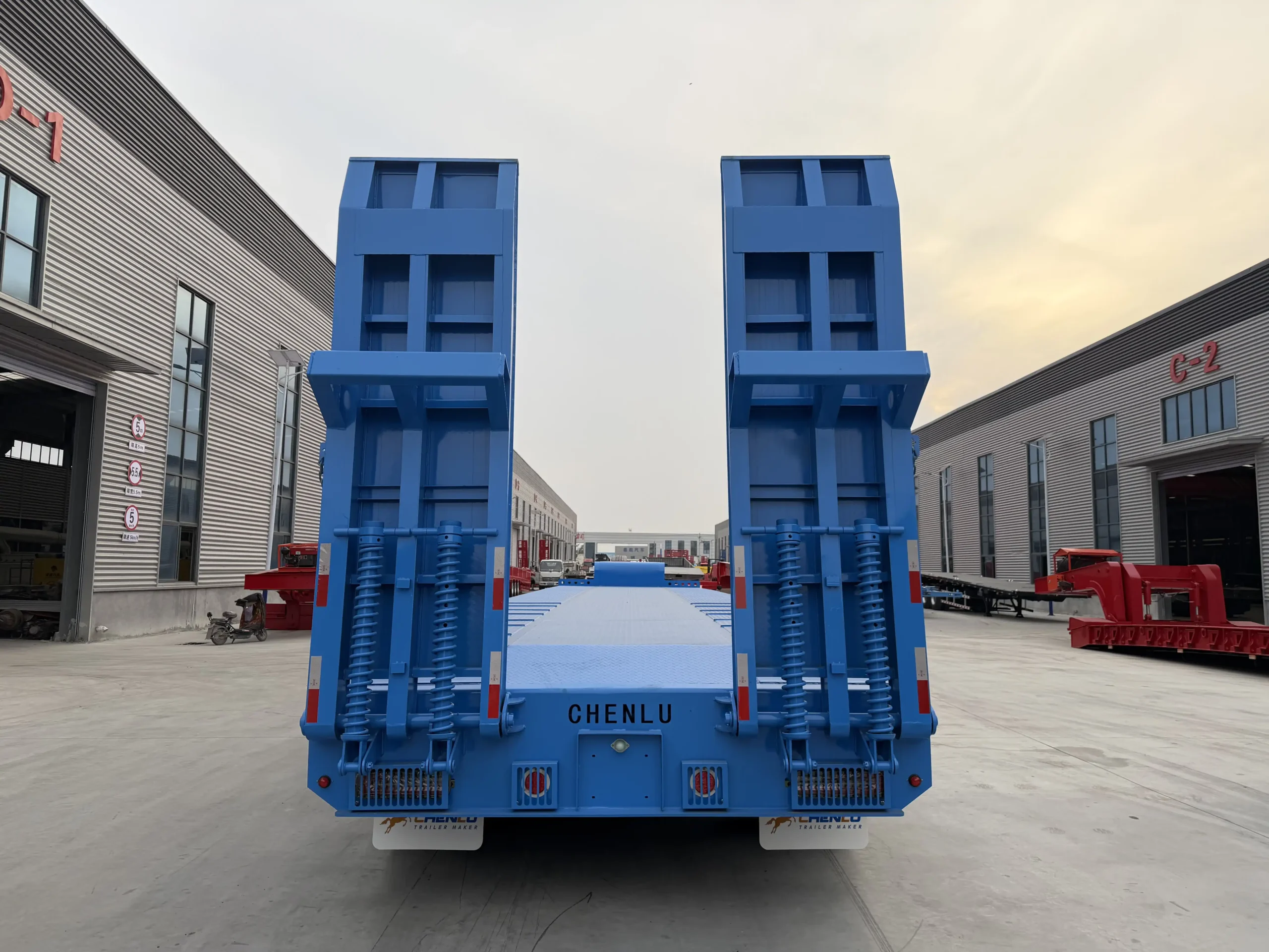 Twin rear loading ramps on a blue fixed neck lowboy trailer