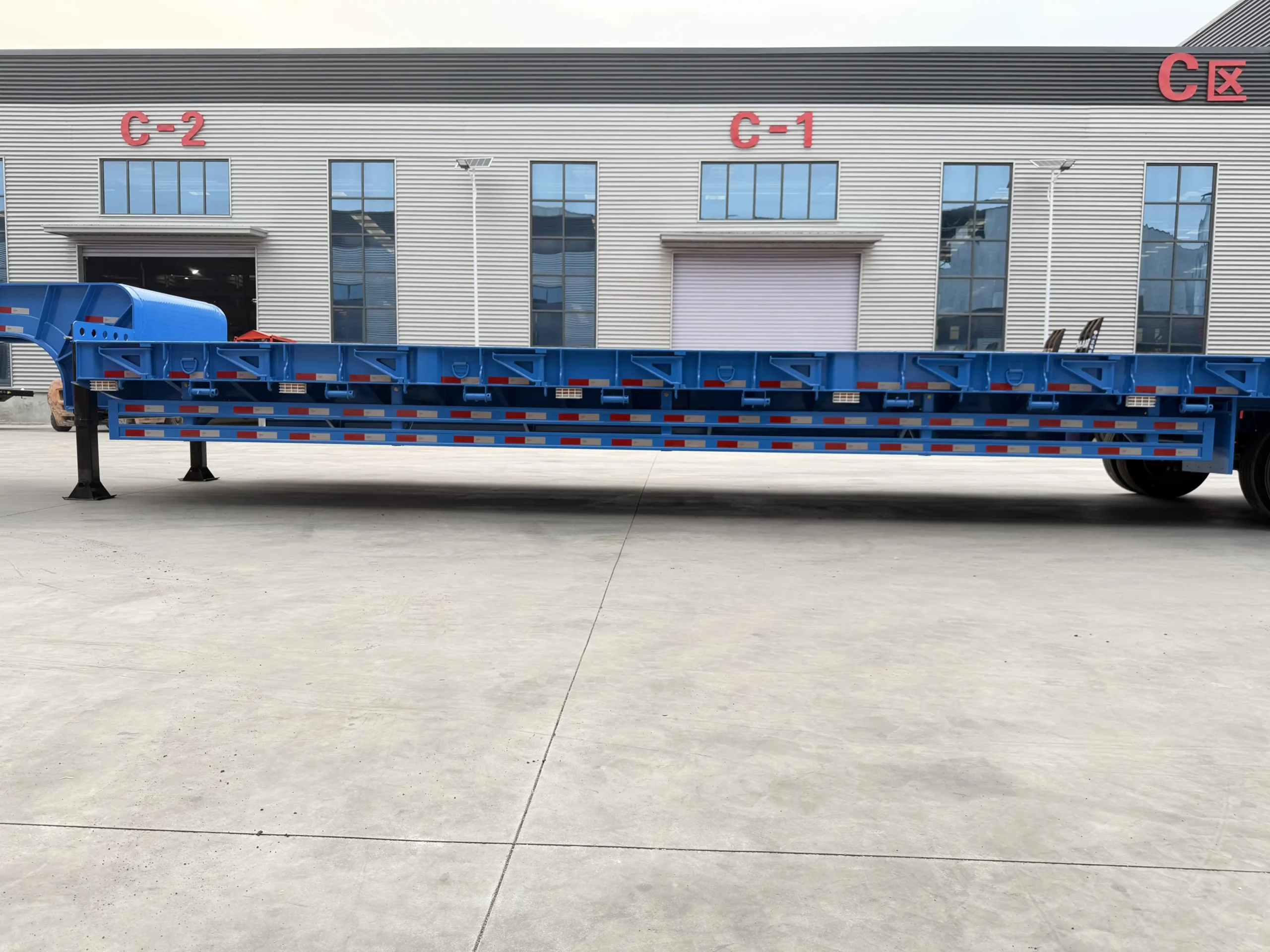 Full side view of a blue 80 ton four axle lowbed trailer