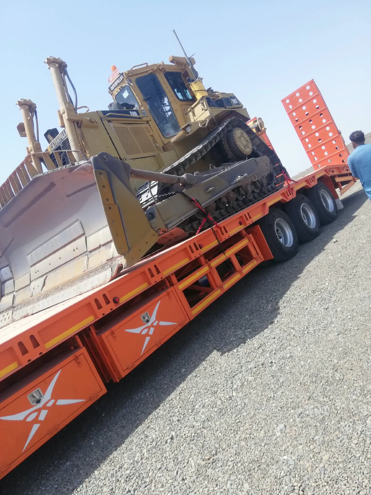 Tracked bulldozer loaded on an orange three-axle lowbed trailer in Oman