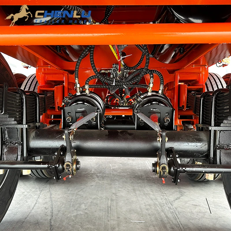 Leaf-spring packs, axle beam and brake chambers under the orange flatbed trailer