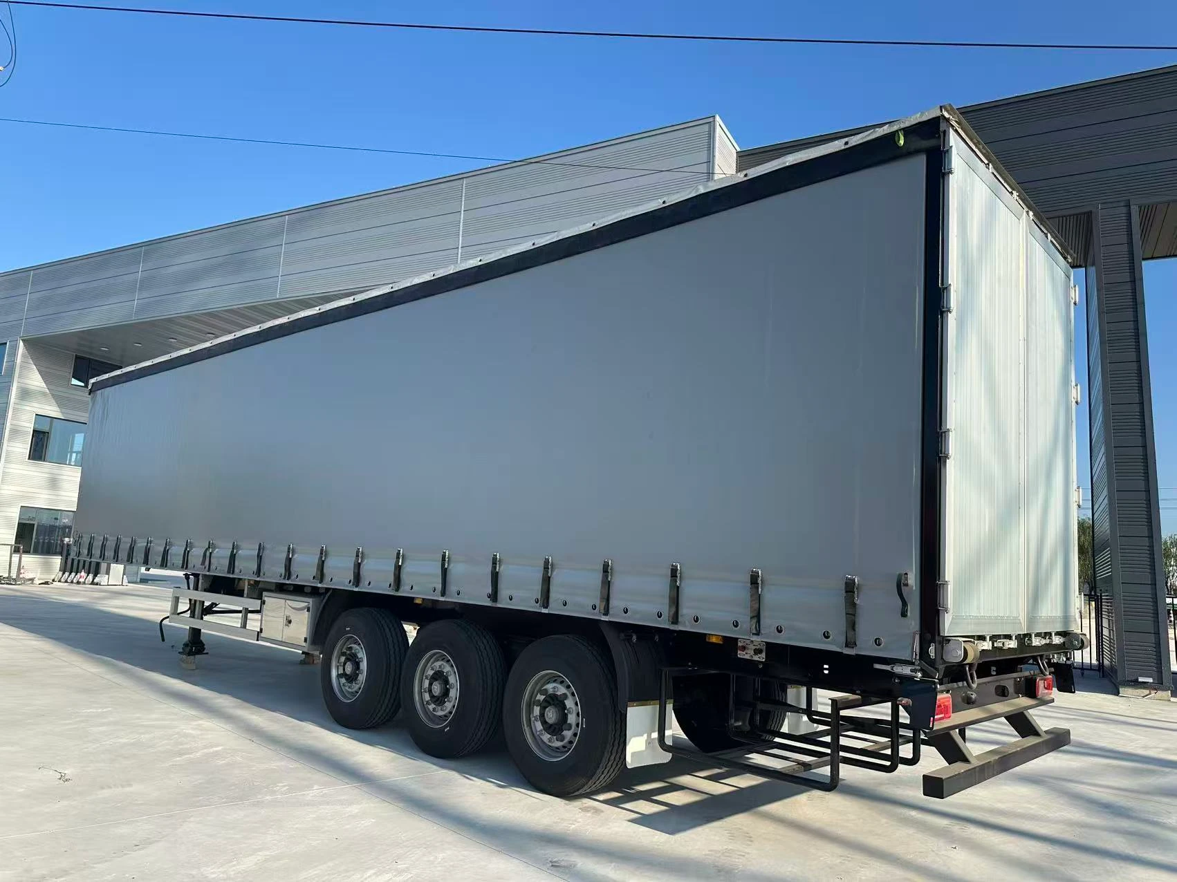 Three-axle curtain side semi trailer with grey side curtain and double rear doors