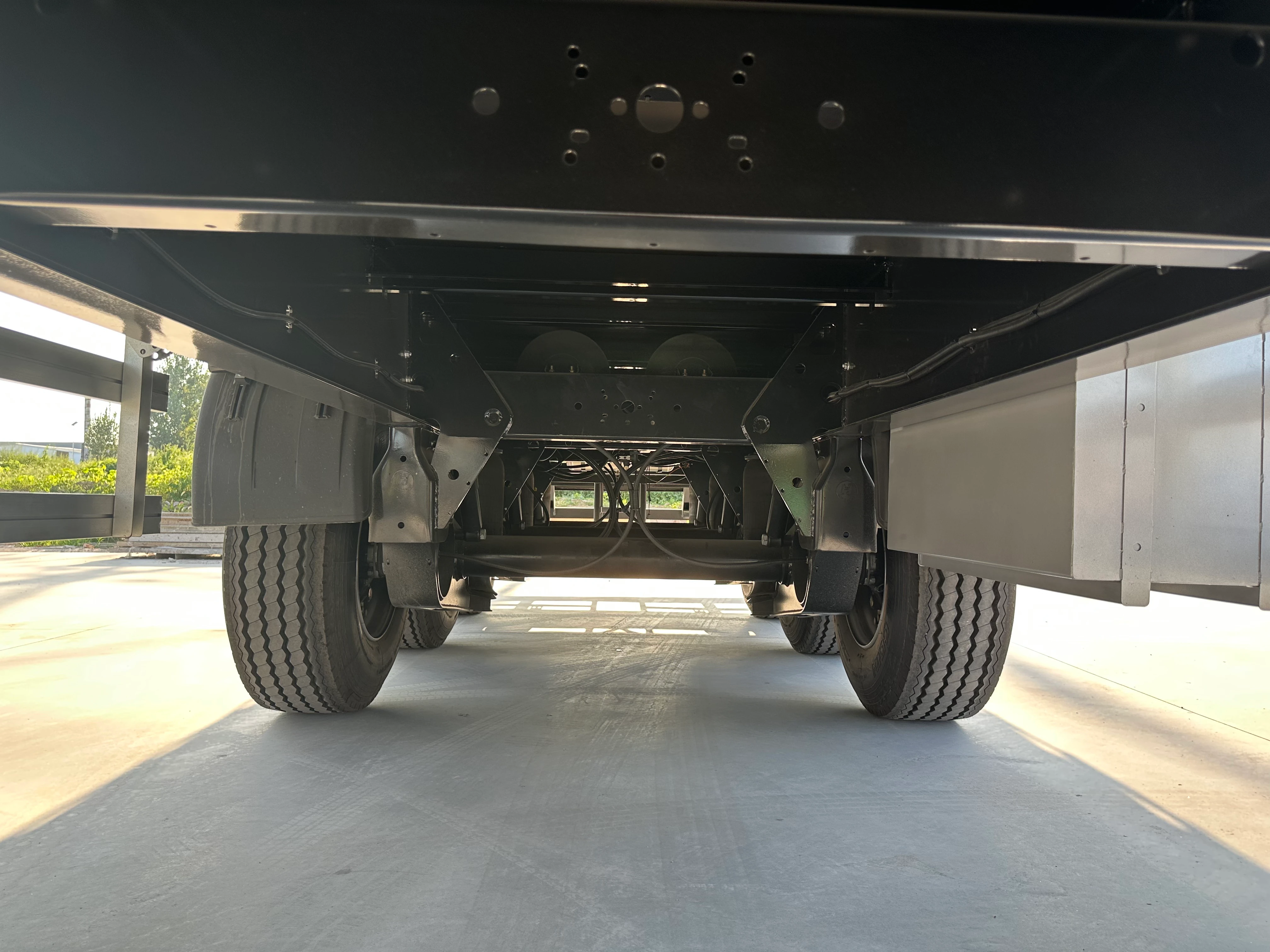 Longitudinal chassis beams and crossmembers beneath the curtain side trailer cargo floor